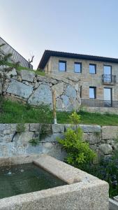 una pared de piedra con un estanque frente a un edificio en CASA DAS QUINTÃES 