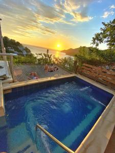 two people laying in a swimming pool with the sunset at Tayrona Colors Hostel in Taganga