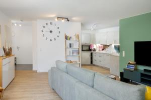ein Wohnzimmer mit einem Sofa und einer Uhr an der Wand in der Unterkunft FENJOY: Ferienapartment mit Balkon / Zentral / BBQ in Bernau am Chiemsee