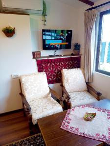 sala de estar con 2 sillas, mesa y TV en Ethno art maisonette in the center of Sofia, en Sofía