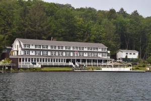 a large building next to a body of water at Chestnut Inn at Oquaga Lake in Deposit