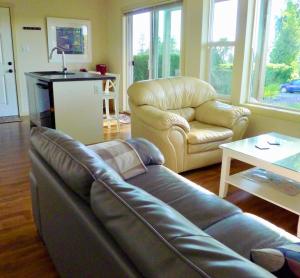 sala de estar con sofá de cuero y silla en AnnArthur Guest House, en Nanaimo