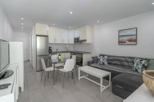 a kitchen and living room with a couch and a table at GO2TENERIFE Apart'Teno Amazing pool view & near the beach in Playa de las Americas
