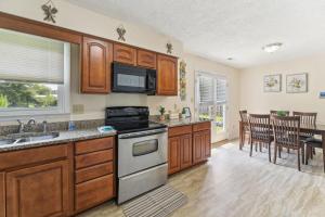 La cuisine est équipée de placards en bois et d'un four avec plaques de cuisson. dans l'établissement Quaint Jacksonville Getaway Near Camp Lejeune!, à Jacksonville