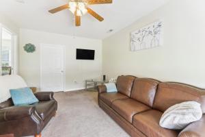 a living room with a brown leather couch and a ceiling fan at Quaint Jacksonville Getaway Near Camp Lejeune! in Jacksonville
