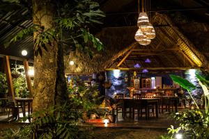 a restaurant with tables and chairs and a tree at Kapievi Ecovillage in Puerto Maldonado