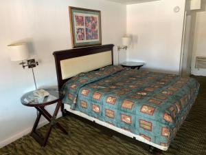 a hotel room with a bed and two tables at Deluxe Inn Austin in Austin