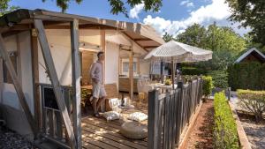 a man standing on a wooden deck in front of a house at Polidor Glamping Resort in Poreč