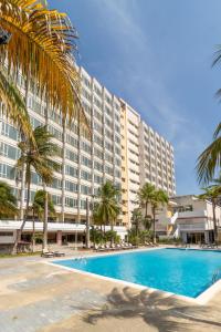 a large hotel with a swimming pool and palm trees at Hotel Faranda Express Puerta del Sol Porlamar in Porlamar