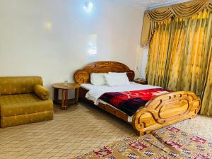 een slaapkamer met een houten bed en een stoel bij Hotel Miandam Palace in Mingora