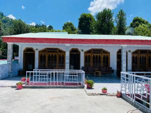 een wit en rood gebouw met een rood dak bij Hotel Miandam Palace in Mingora