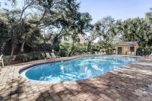 a swimming pool with chairs and trees at 207 Sailmaker in Fernandina Beach