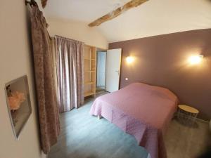 ein Schlafzimmer mit einem rosa Bett in einem Zimmer in der Unterkunft Gîte le Récantou maison au cœur du village in Duillac
