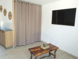 ein Wohnzimmer mit einem Couchtisch und einem Flachbild-TV in der Unterkunft Gîte le Récantou maison au cœur du village in Duillac