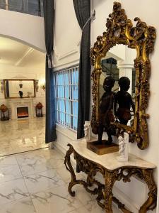een spiegel en een standbeeld op een tafel in een kamer bij The Peacock Mansion in Kumasi