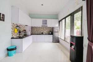 uma cozinha com armários brancos e uma grande janela em The Fortune Guest House em Tejakula