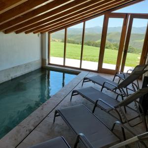 un grupo de sillas sentadas junto a una piscina en Villa Brenagudina - Cabaña Pasiega con piscina climatizada, en San Pedro del Romeral