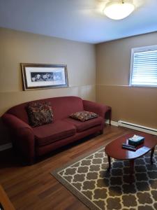 a living room with a red couch and a table at Lovely 2 Bedroom apartment close to Avalon Mall in St. John's