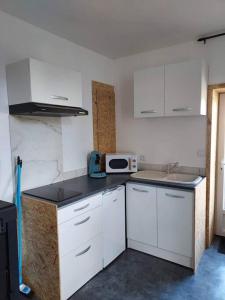 una pequeña cocina con armarios blancos y microondas en Petite maison de campagne en Castillon-de-Castets