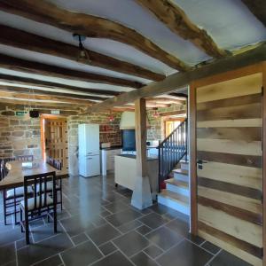 cocina y comedor con mesa y nevera en Villa Brenagudina - Cabaña Pasiega con piscina climatizada, en San Pedro del Romeral