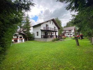 a white house with a green lawn in front of it at Vila Alunis 2 in Bran