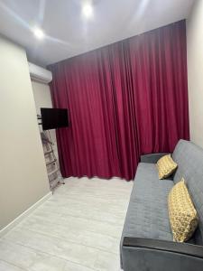 sala de estar con sofá y cortina roja en Люксовая Квартира, en Aktobe