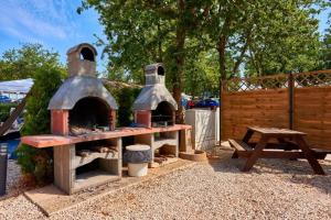 a outdoor oven with a picnic table and a bench at Polidor Glamping Resort in Poreč