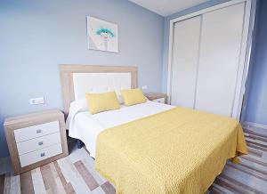 a bedroom with a bed with a yellow blanket at Apartamentos de Playa en el centro de O Grove in O Grove