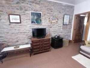 a living room with a tv and a stone wall at LÍRIOS DA GRANJA - CASA DE CAMPO in Granja