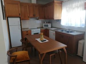 a kitchen with a wooden table and a white refrigerator at LÍRIOS DA GRANJA - CASA DE CAMPO in Granja