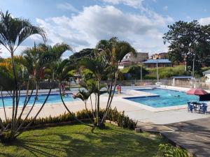 a swimming pool in a resort with palm trees at Hermoso Apartamento en Mesitas de El Colegio in El Colegio