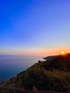 uma vista para o oceano ao pôr-do-sol a partir de uma colina em Koumaros Villas em Agia Paraskevi