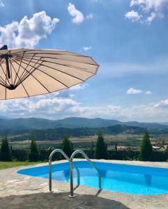 a umbrella next to a swimming pool with a view at Villa Monte in Velingrad