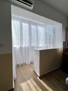 a room with two large windows with white curtains at Lara Residence in Băile Herculane