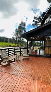 una terrazza in legno con 2 sedie e un gazebo di Pousada Cachoeira da Neve- Chalé Quero Quero a Urubici
