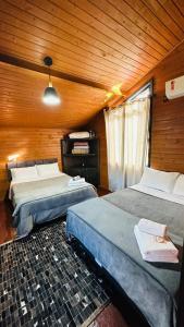 een slaapkamer met 2 bedden in een houten kamer bij Pousada Cachoeira da Neve- Chalé Quero Quero in Urubici