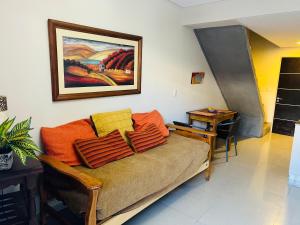 uma sala de estar com um sofá e uma pintura na parede em Hermoso Departamento con patio zona sur em San Miguel de Tucumán