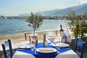 a table with a blue table cloth and wine glasses at Kotronas Bay Bungalows in Kotronas