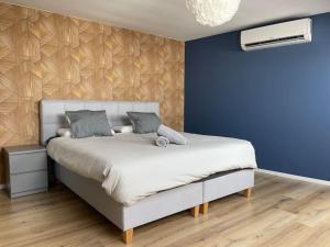 - une chambre avec un grand lit et un mur bleu dans l'établissement Duplex 100m2 style contemporain, à Seraing