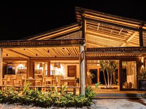 a wooden building with wooden tables and chairs at Pousada Nossa Casa Cumuruxatiba in Cumuruxatiba