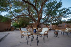 einen Tisch und Stühle mit einem Baum im Hintergrund in der Unterkunft Hotel Don Raul in San Pedro de Atacama