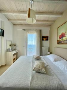 a bedroom with a large white bed and a window at Koumaros Villas in Agia Paraskevi