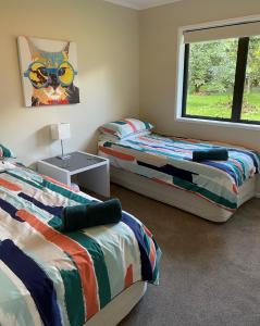1 dormitorio con 2 camas y una pintura de un gato en Baybell Lodge en Omanawa