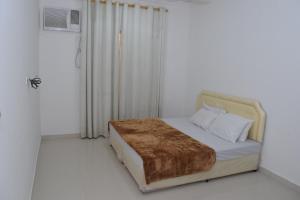 a white bedroom with a bed with a brown blanket at RED Alwadi Salalah in Salalah