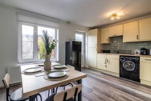 a kitchen with a table with chairs and a refrigerator at Cosy Home - Contractors Welcome - Garden & Free Parking in Derby