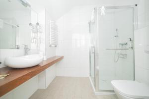 ein weißes Bad mit einem Waschbecken und einer Dusche in der Unterkunft VacationClub - Stubai Apartament 38 in Heudorf