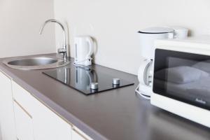 a kitchen counter with a sink and a microwave at VacationClub - Bormio Apartament 8 in Sienna