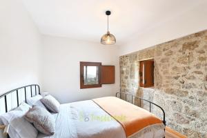 um quarto com uma cama e uma parede de pedra em Casa do Alfaiate by TonsdeVerde em Vila Verde
