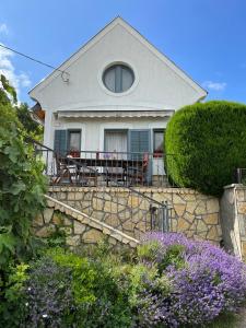 a house with a table and chairs on a stone wall at Hegyi Füge Vendégház in Csopak