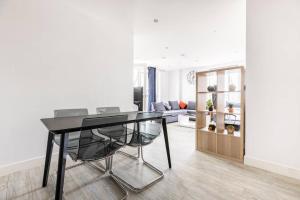 Stylish & Comfortable Top-Floor Flat in Harrow في لندن: غرفة طعام مع طاولة سوداء وكراسي